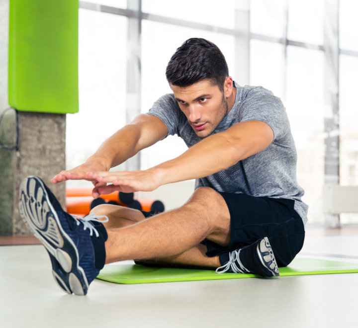 fitness man doing stretching exercises at gym