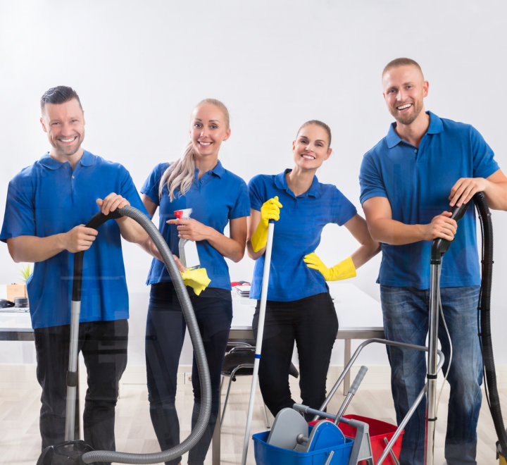 happy male and female janitors with cleaning equipment