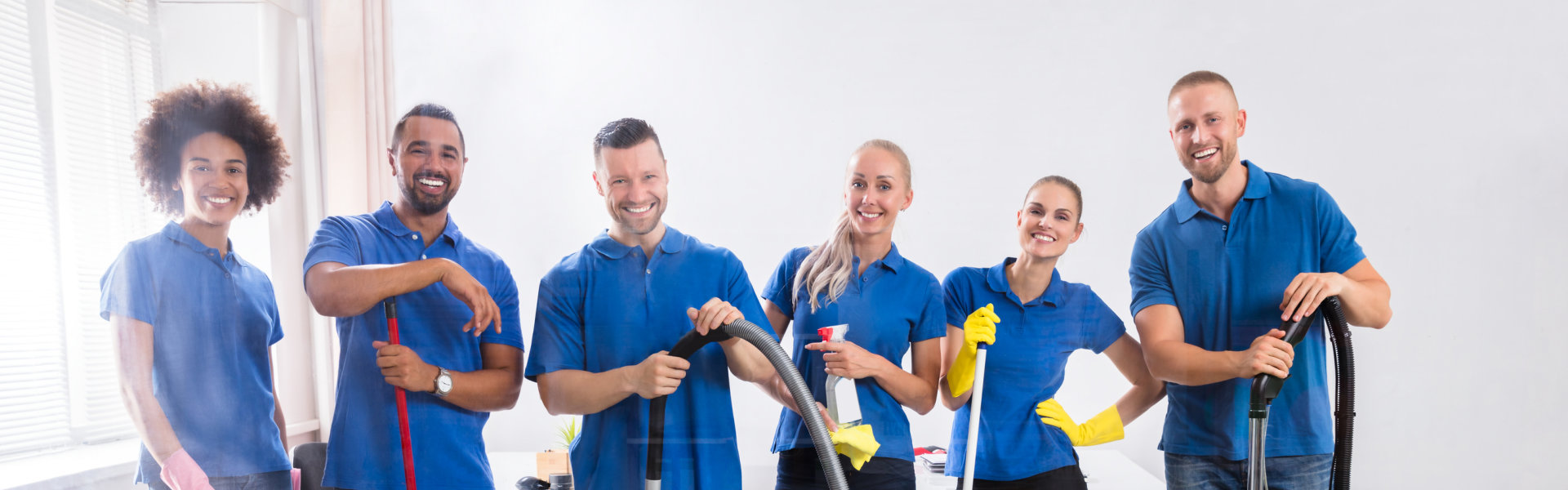 happy janitors with cleaning equipment